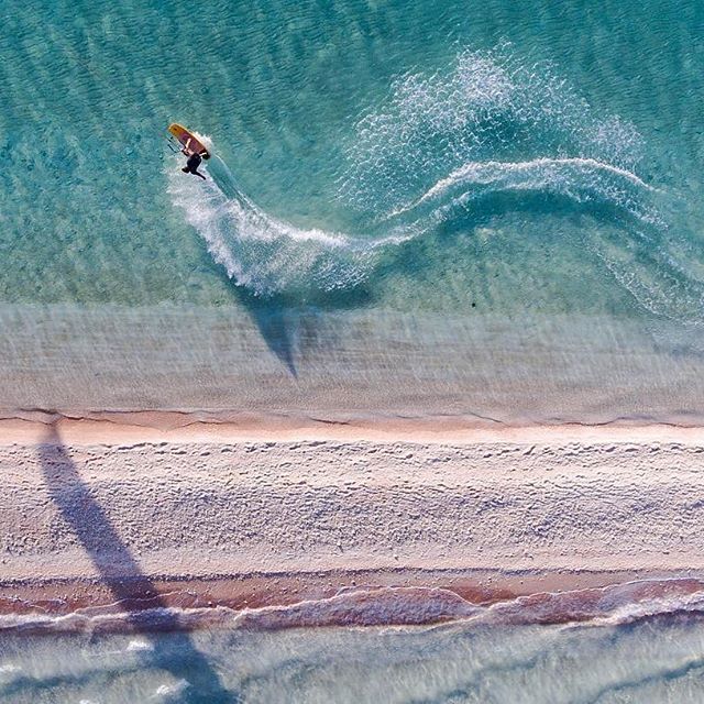 Snake your way into the weekend! Here's a guest from @reostevens' Tuamotu Sailing Adventure carving alongside pink sand in some of the smoothest water you can imagine. Photo: @reostevens